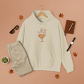 Beige hoodie with 'Fall into Gardening' design on a peach background with accessories.