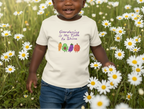 Child wearing a t-shirt with 'Gardening is My Time to Shine' and vegetable graphics in a field of flowers.