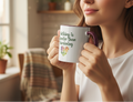 Person holding a mug with 'Nothing is sweeter than gardening' text in a cozy indoor setting.