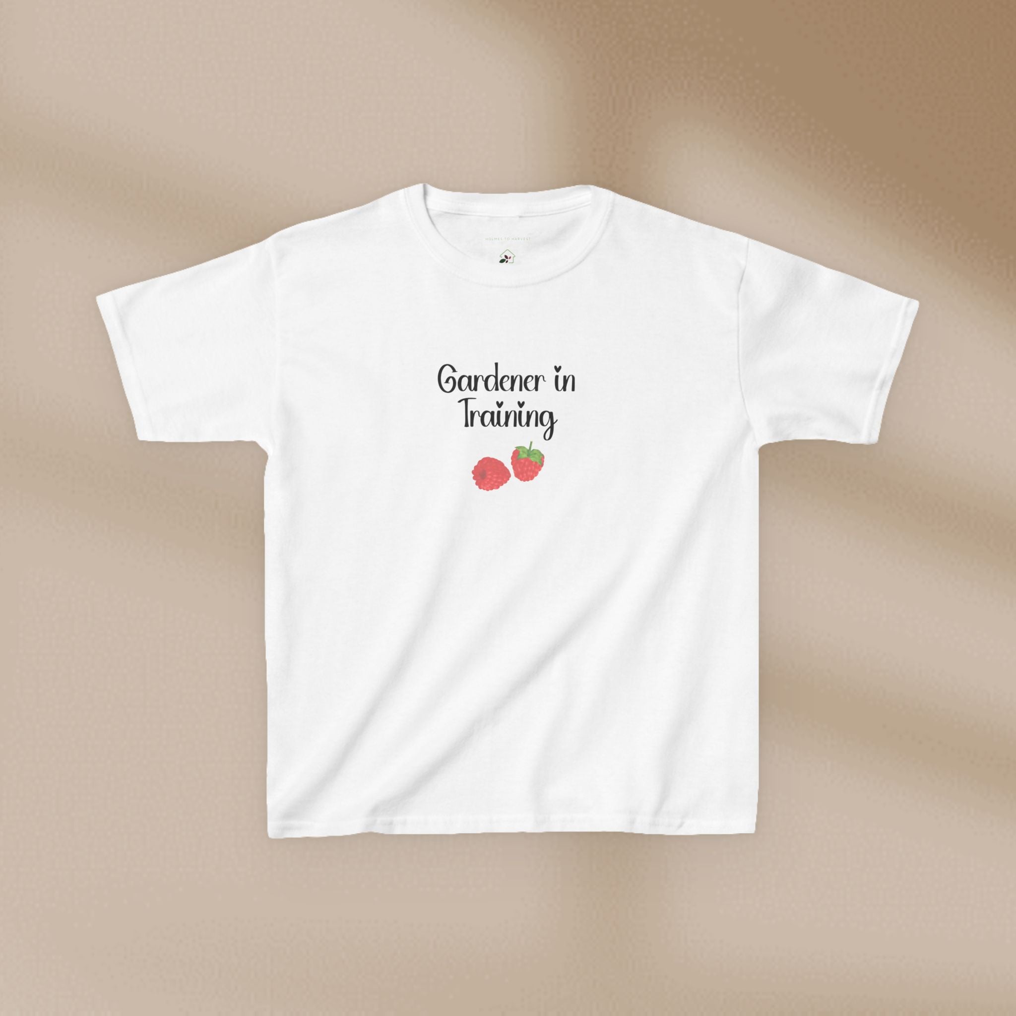 White t-shirt with 'Gardener in Training' text and strawberry graphics on a beige background