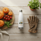 White water bottle with a design on a wooden surface with pumpkins, tomatoes, and gloves.