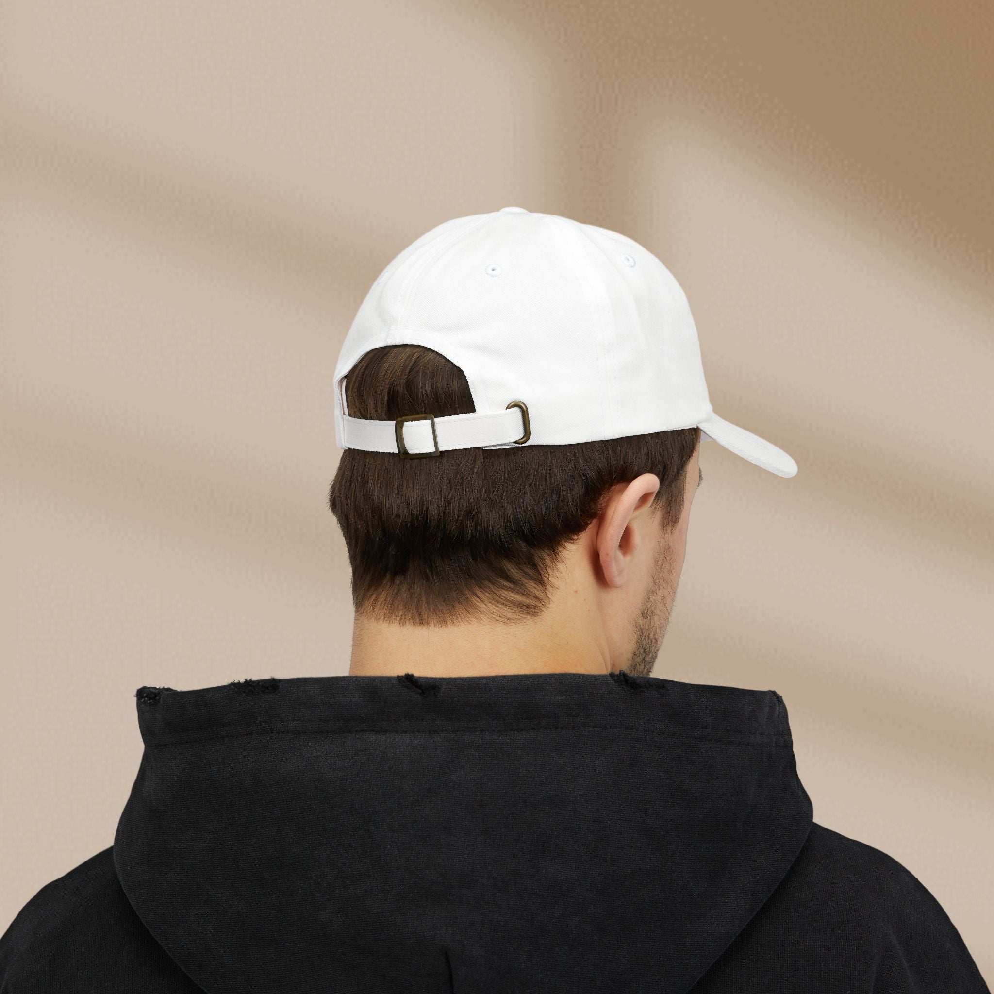 Person wearing a white cap and black hoodie from behind on a beige background