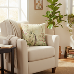 Beige armchair with floral pillow, blanket, and cup in a cozy living room.