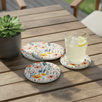 Floral coasters on a wooden table with a glass of lemonade and a potted plant.