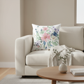 Floral pillow on a beige sofa with a wooden coffee table in a living room setting.