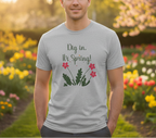 Man wearing a t-shirt with 'Dig in, It's Spring!' text and floral design in a garden setting