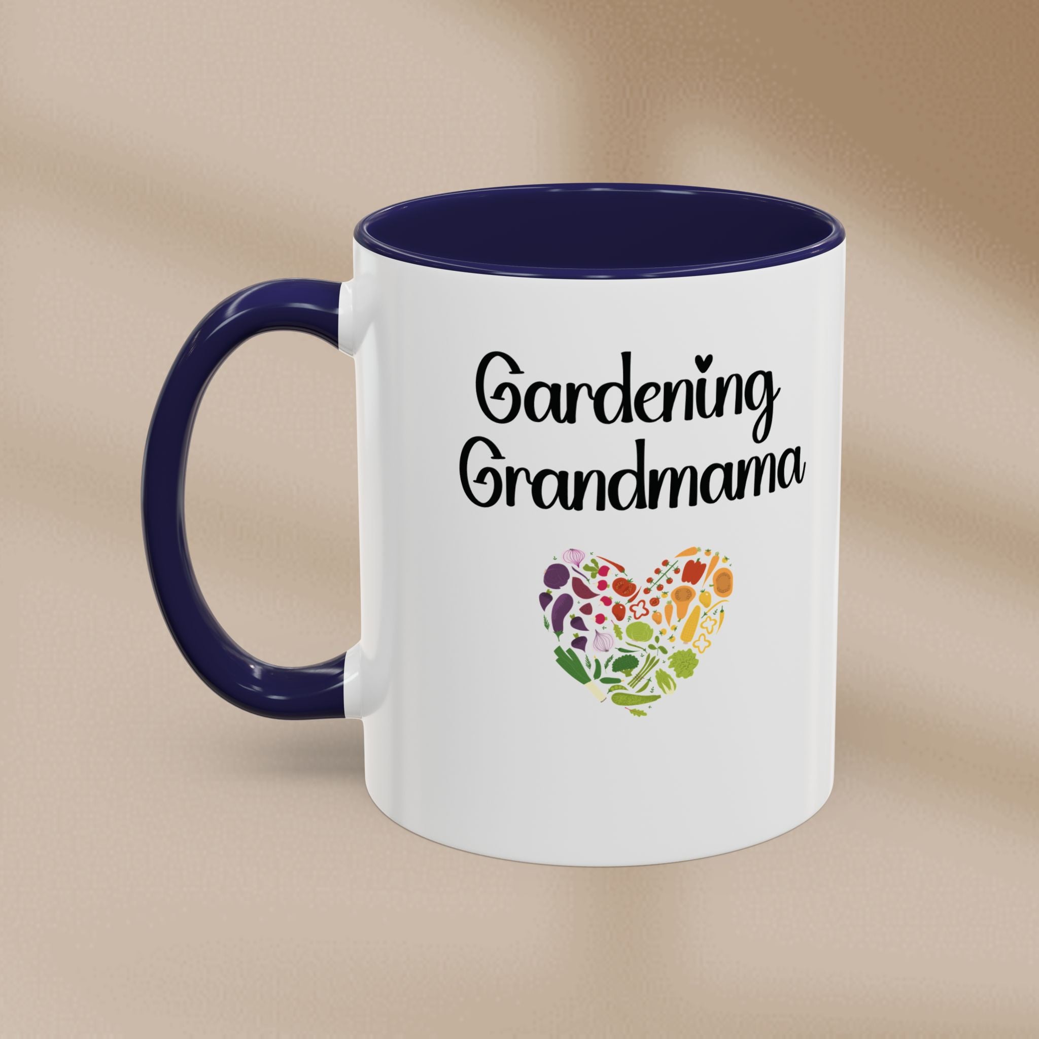 White mug with blue handle featuring 'Gardening Grandmama' text and heart-shaped floral design on a beige background