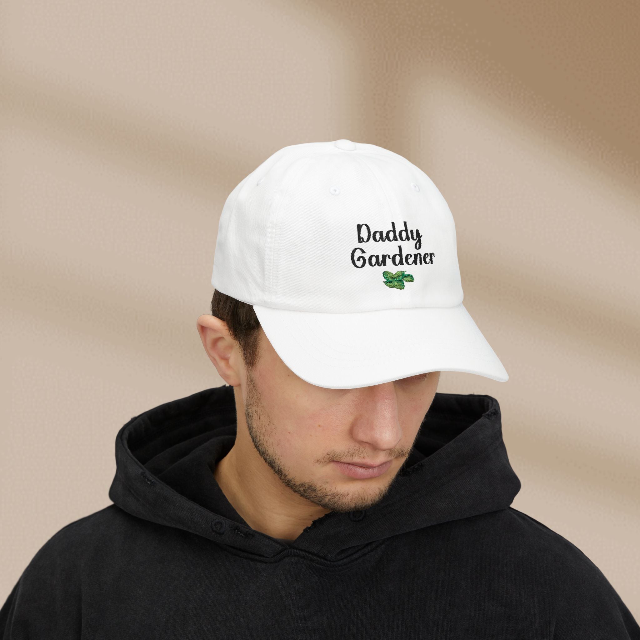 Person wearing a white cap with 'Daddy Gardener' text on a beige background
