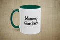 White mug with green handle and interior, featuring 'Mommy Gardener' text on a beige background