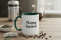 Mug with 'Mommy Gardener' text on a table with coffee beans and tea leaves.