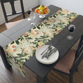 Dining table with floral table runner, plates, cutlery, and fruit bowl.