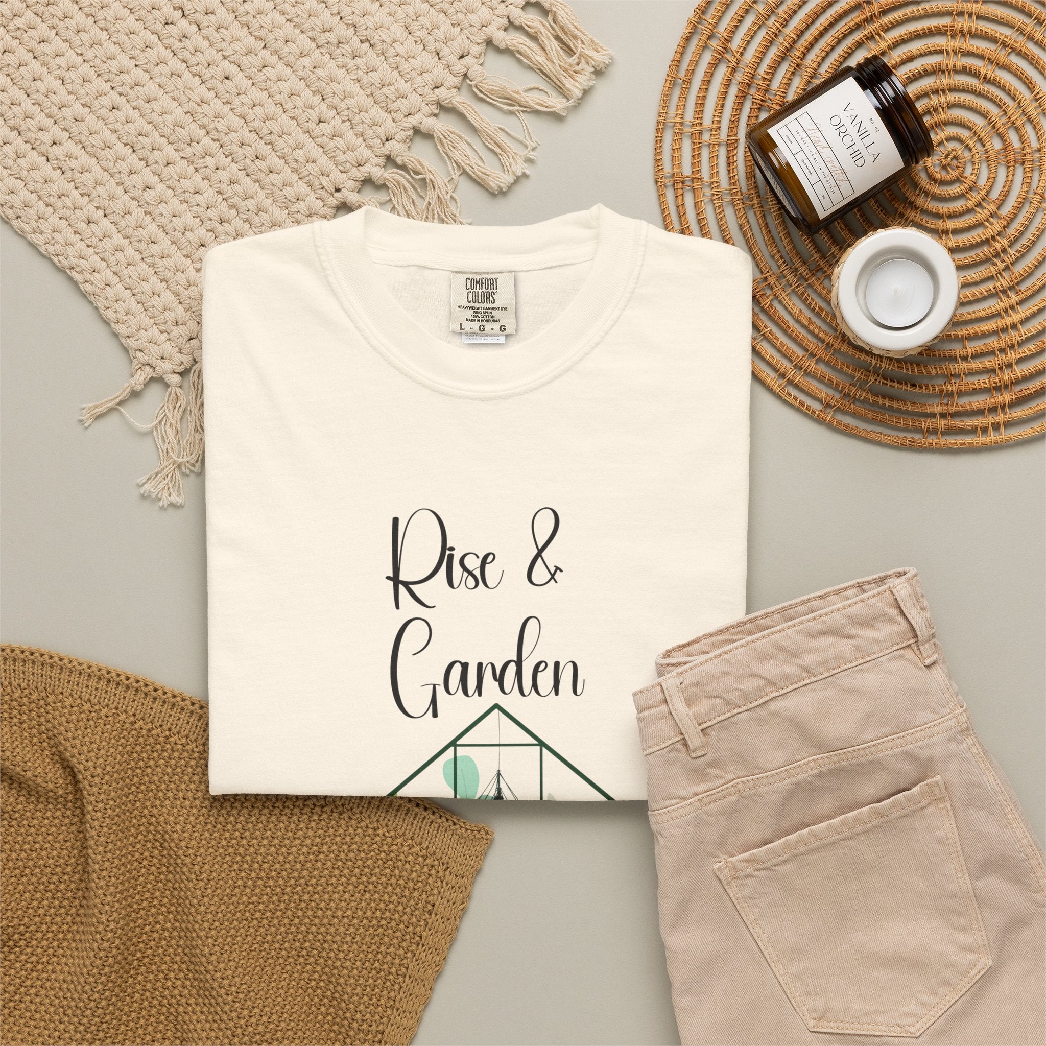 White t-shirt with 'Baby Girl In Progress' text on a neutral background with beige pants and decorative items.
