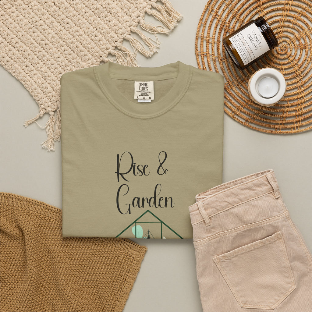 Folded olive green t-shirt with 'Rise & Garden' text on a neutral background