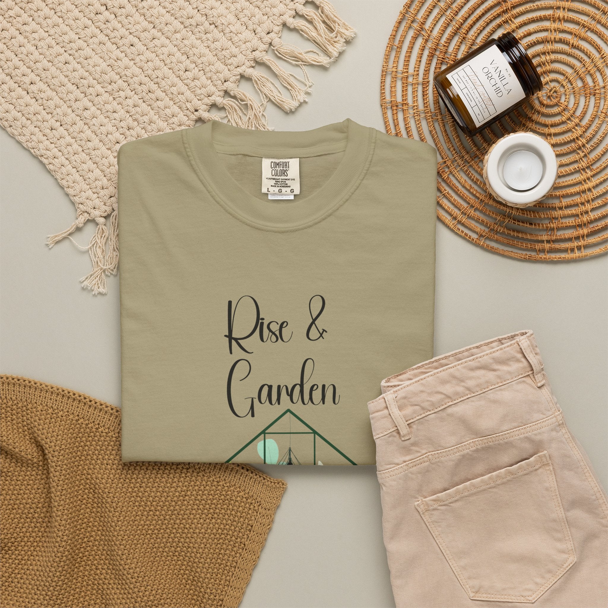 Folded olive green t-shirt with 'Rise & Garden' text on a neutral background