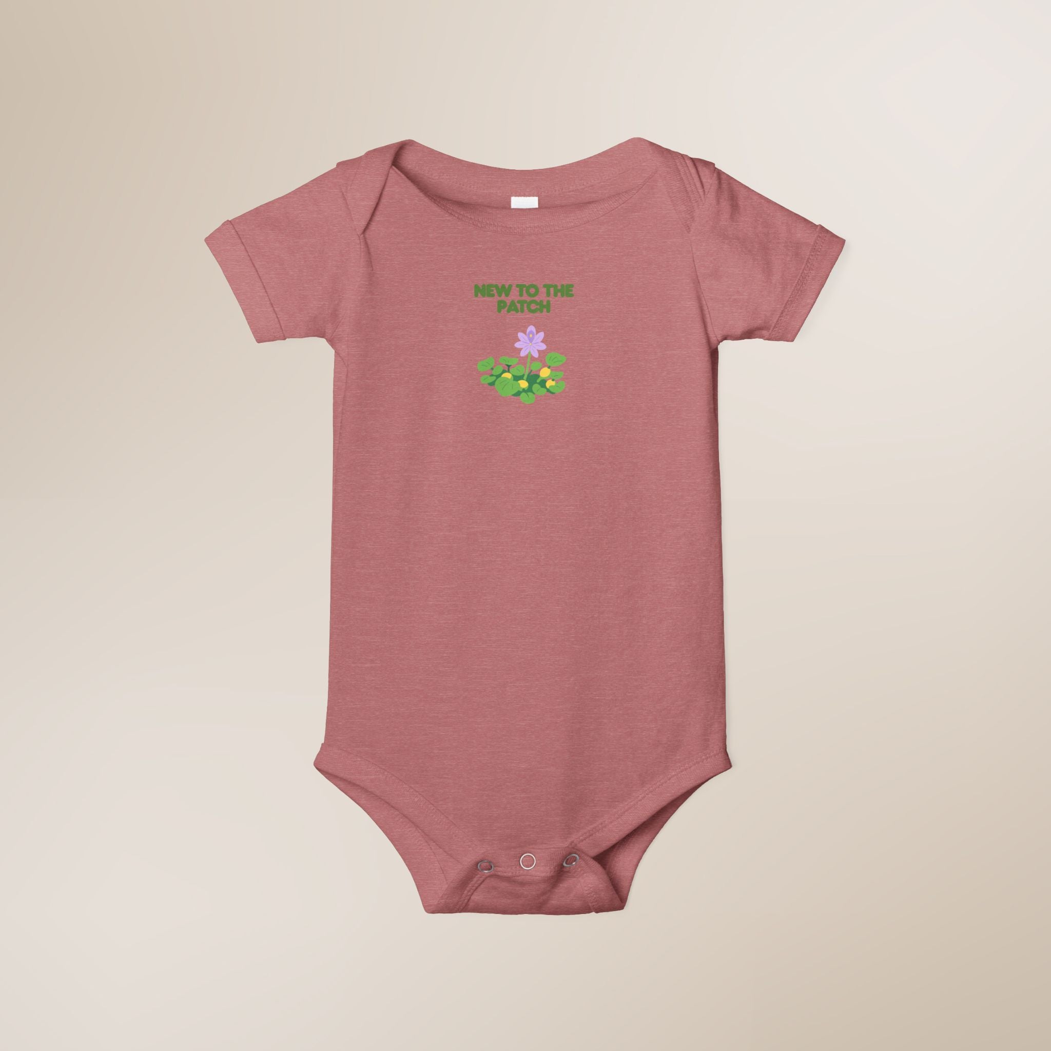 Pink baby onesie with text and graphics on a beige background