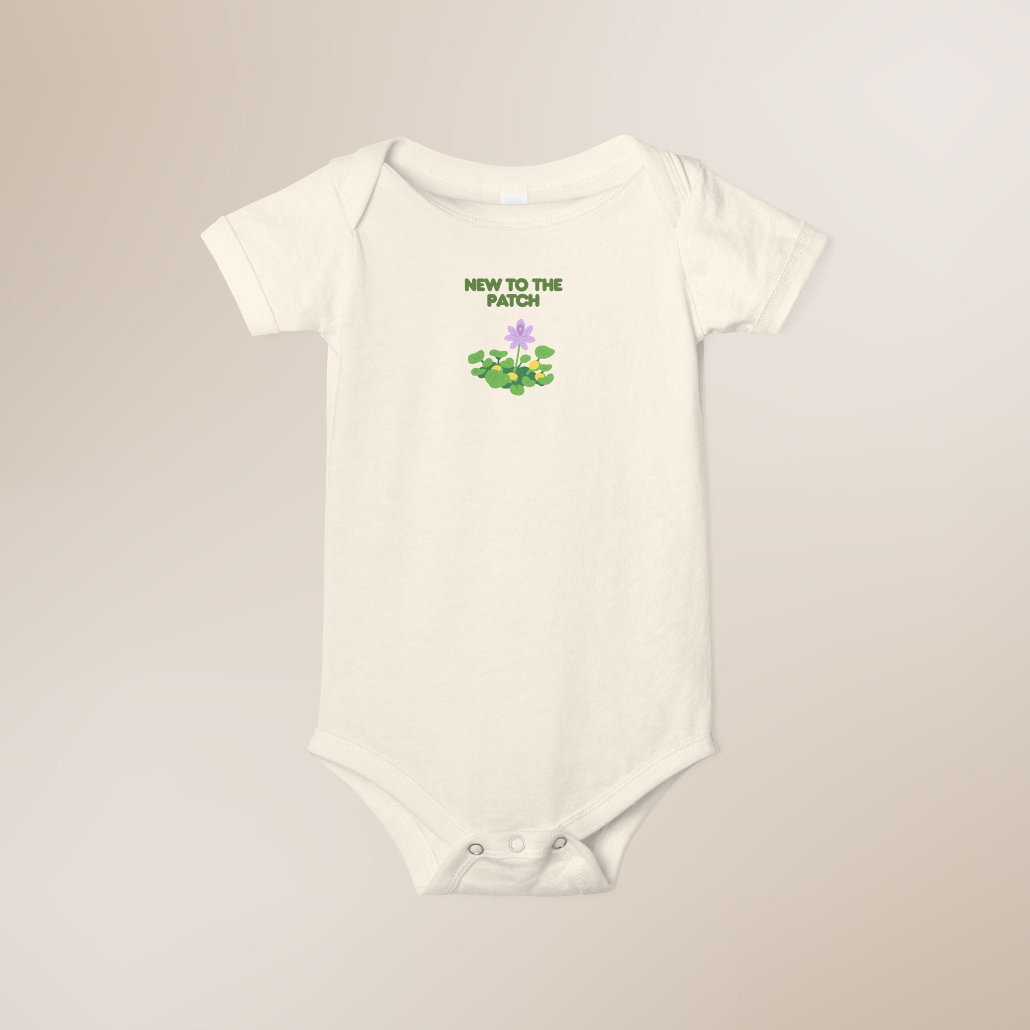 White baby onesie with 'New to the Patch' text and graphic on a beige background