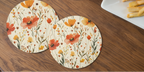 Floral coasters on a wooden table with a cup of tea and fries.