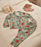 Floral pajama set on a bed with a book and towel.
