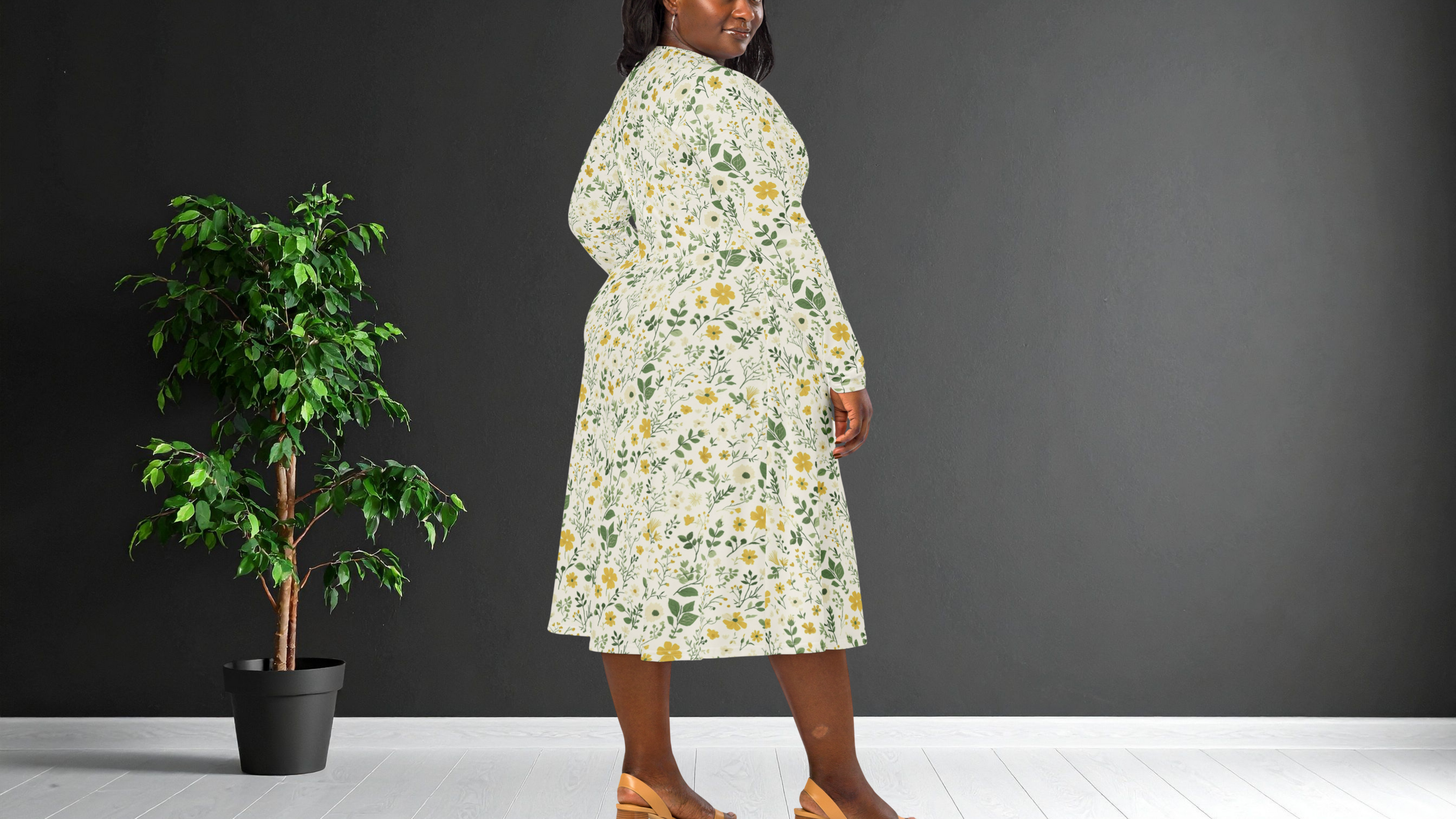 Woman wearing a floral dress standing next to a potted plant against a dark wall.