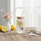 Glass jar with a wooden lid, lemonade, and flowers on a wooden table.