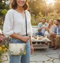 Woman holding a floral-patterned bag in an outdoor setting with friends around a table.