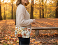 Woman holding a floral-patterned bag in an autumn park