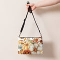 Handbag with floral design held by a hand against a beige background