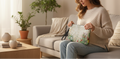 Woman sitting on a couch holding a floral-patterned bag in a cozy living room.