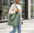 Woman holding a green striped tote bag in an urban setting