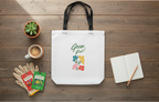 White tote bag with 'Grow Girls' design on a wooden surface with gardening items.