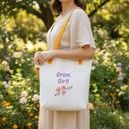 Person holding a tote bag with 'Grow, Girl!' text in a garden setting