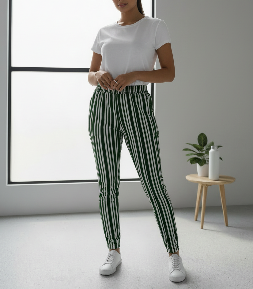 Person wearing a white t-shirt and green striped pants in a minimalistic room.