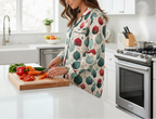 Person in a kitchen wearing a patterned apron, cutting vegetables on a cutting board.
