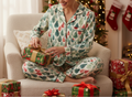 Person in festive pajamas sitting on a couch with Christmas presents and decorations.