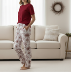 Person wearing a red top and patterned pants standing in a living room.