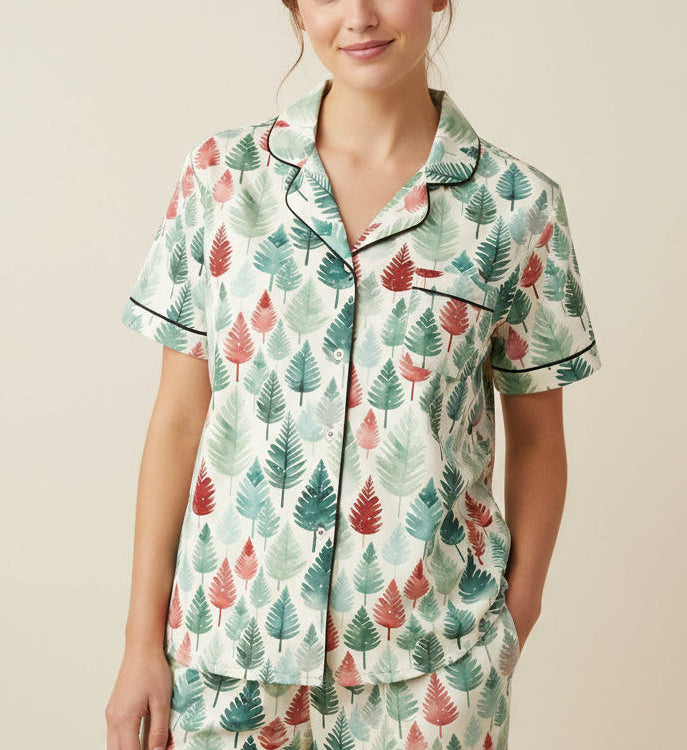 Person in festive pajamas surrounded by Christmas presents in a living room.