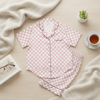 Floral pajama set on a light wooden surface with a blanket and cup of tea.