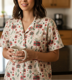 Woman in a festive pajama top holding a mug in a kitchen.