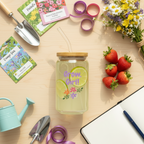 Jar with 'Grow, Girl!' text on a table with gardening tools and strawberries