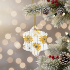 Decorative ornament with yellow flowers hanging on a Christmas tree branch with pine cones and berries.