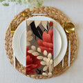 Floral design card on a table setting with plates, cutlery, and a woven placemat.
