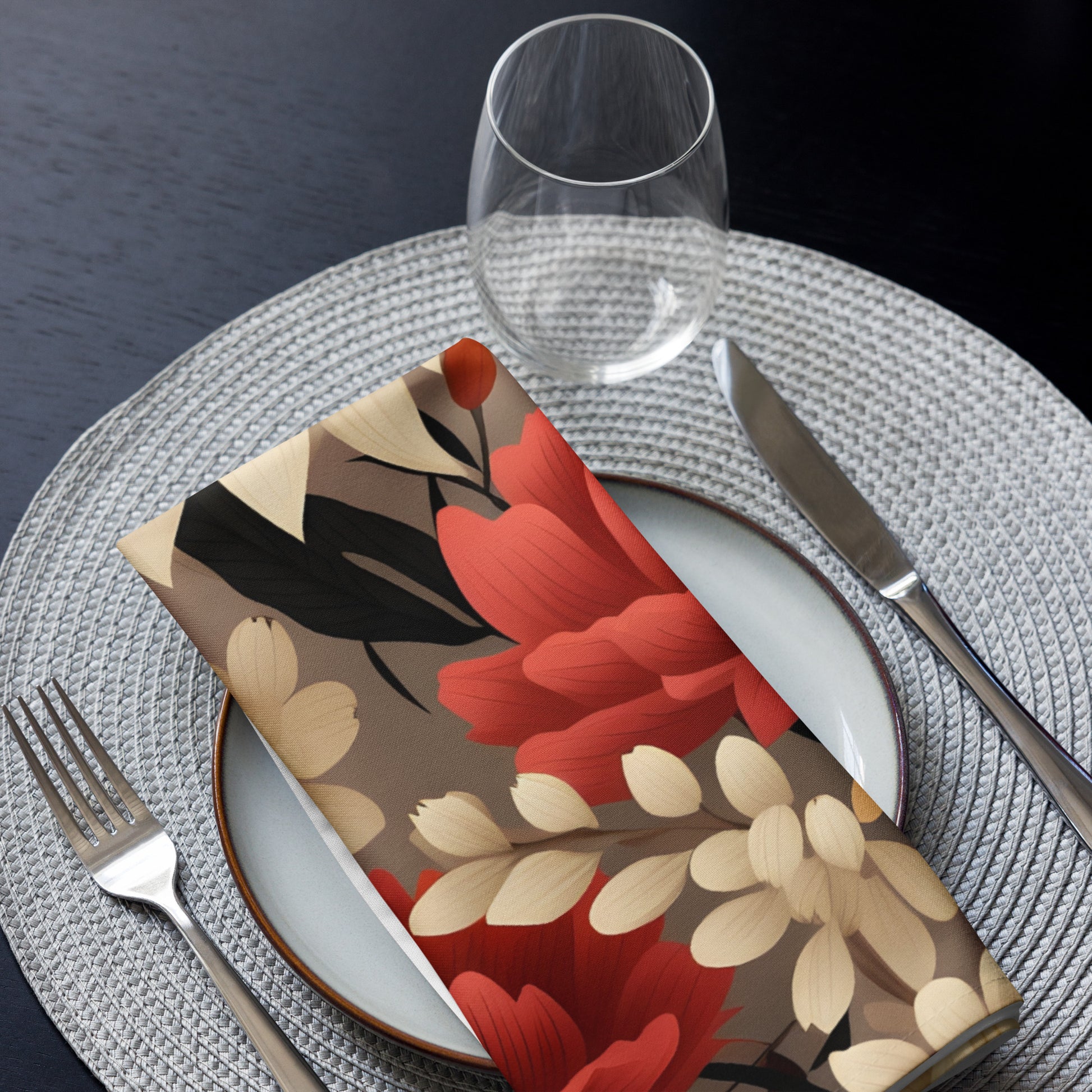 Floral-patterned napkin on a table setting with cutlery and glass.