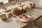 Dining table set for a meal with plates, cutlery, and decorative items.