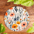 Floral patterned coaster on a wooden surface with leaves around