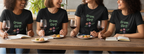 Four women sitting at a table wearing black t-shirts with 'Grow, Girl!' text, enjoying wine and food.