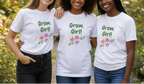 Three women wearing white t-shirts with 'Grow, Girl!' text in a garden setting.
