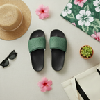 Green and black slides with a straw hat, sunglasses, and flowers on a light surface